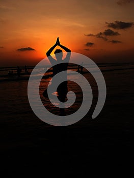 Man Posing in Vriksha Asana Yoga Pose on the sea beach during sunrise photo