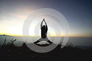 Man posing yoga on top of misty mountain cliff