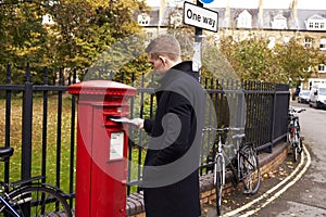Man Posting Letter In Red British Postbox