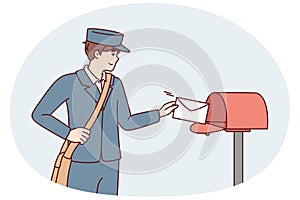 Man in postman uniform throws paper letter into metal mailbox located on street