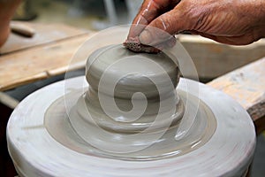 Man potter hands working on pottery clay wheel