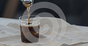 man pour cola over ice rocks into tumbler glass