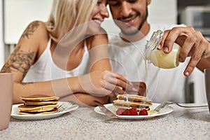 Man pour condensed milk on pancakes and girlfriend