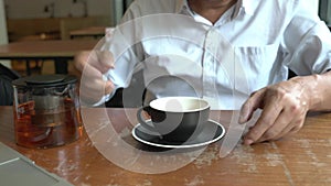 Man pour hot black tea from teapot to empty cup and drink from it.