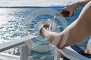 Man pouring beer into mug on seaside deck
