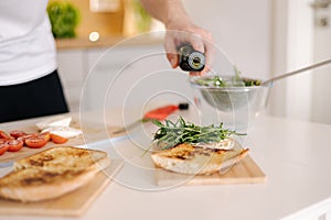 Man pouring cold pressed linseed oil on classic Italian bruschetta. Vegan healthy food