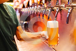 Man pouring craft beer from beer taps in frozen glass with froth. Selective focus. Alcohol concept. Vintage style. Beer craft