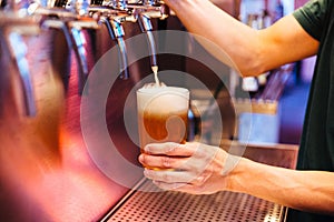 Man pouring craft beer from beer taps in frozen glass with froth. Selective focus. Alcohol concept. Vintage style. Beer craft.