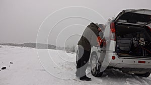 Man pouring gasoline into an empty fuel tank in winter offroad adventure