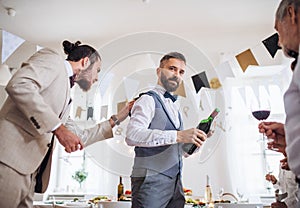 A man pouring guests wine on a indoor family birthday party.