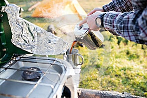 Man Pouring Hot Coffee In Cup While Camping