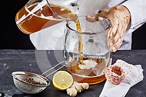 Man pouring kombucha SCOBY tea into jar photo