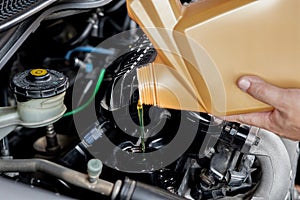 A man Pouring oil to car engine. Fresh oil poured during an oil change to a car Adding engine oil