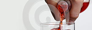 Man pouring orange drink into glass with ice closeup