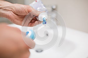 Man pouring toothpaste on a toothbrush