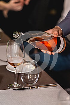 Man pouring vine from the bottle into glass in detail. wine tasting