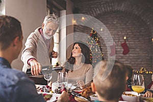 Man pouring wine for family Christmas dinner