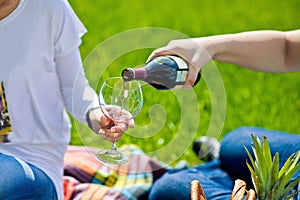 Man pouring woman a glass of red wine at picnic