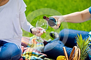 Man pouring woman a glass of red wine at picnic