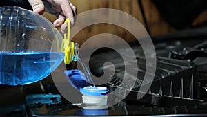A man pours anti-freeze cleaning fluid for a car windshield. Close-up
