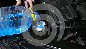 A man pours anti-freeze cleaning fluid for a car windshield. Close-up