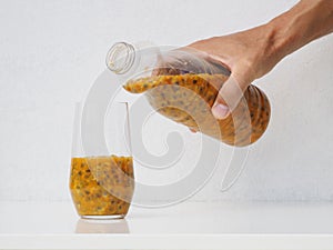 Man pours from a bottle in glass fresh passion fruit maracuya juice.