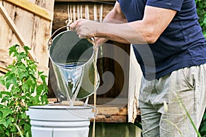 Man pours into a bucket of water just taken from the well