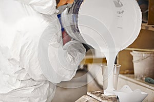 Man pours dosed amount of paint in a plastic cup. photo