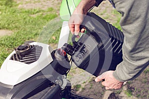 A man pours gasoline from the canister into the cultivator tank