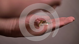 A man pours a handful of pills into his palm on a light background, close-up