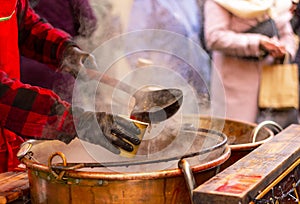 man pours hot mulled wine into a glass with a ladle, hands close-up. gluhwein, drink. winter holidays