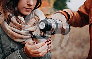 Man pours hot tea out of thermos in autumn forest