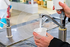Man pours mineral water in glass in pump-room