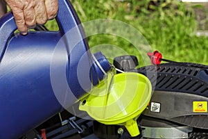 A man pours oil on his lawn mower