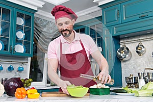 Man pours olive oil in bowl with vegetable salad. Preparation of tasty and healthy food at home. Cooking and home concept - male