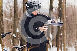 Man pours tea from a thermos. Winter forest. Close-up.