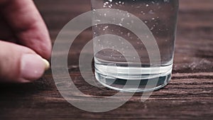 Man pours water into a glass and puts down pills.