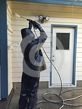 Man power washing a home.