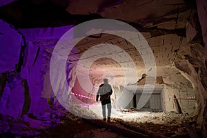 A man with powerful flashlights explores dangerous tunnels, old abandoned quarry mines near the city of Sataniv, Ukraine. Cracks