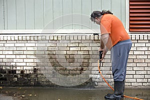 Man powerwashing mold of wall - DIY