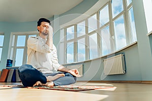 Man practice yoga. Young attractive male doing breathing exercises. Guy meditating at home along during the pandemic