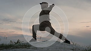 A man practices yoga outdoors at a beautiful sunset. Pilates in nature, athletic man doing exercises for health