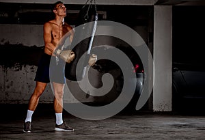 Man practicing boxing on big black bag in garage