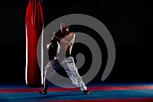 Man practicing boxing on big black bag in gym