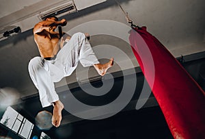 Man practicing boxing on big red bag in gym