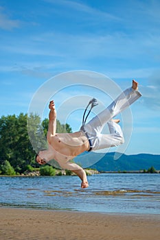 Man practicing capoeira on the beach. The man does the fighting element of capoeira.