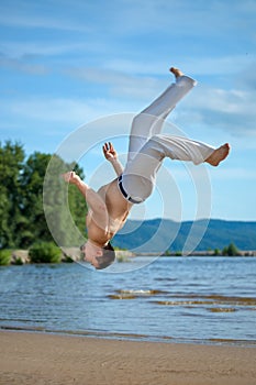 Man practicing capoeira on the beach. The man does the fighting element of capoeira.