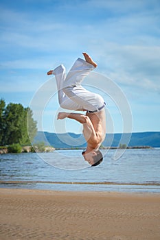 Man practicing capoeira on the beach. The man does the fighting element of capoeira.