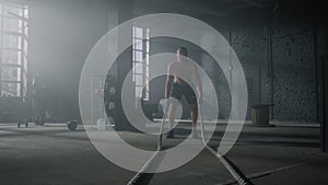 Man practicing exercise with battle ropes. Sportsman doing functional training