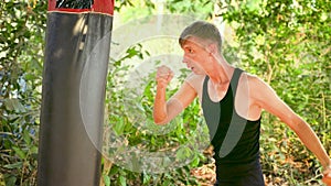 man is practicing his strikes on a punching bag in an Asian country